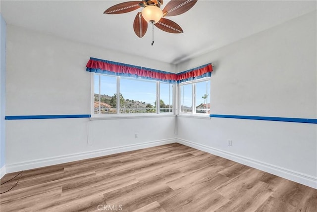 unfurnished room featuring a ceiling fan, wood finished floors, and baseboards