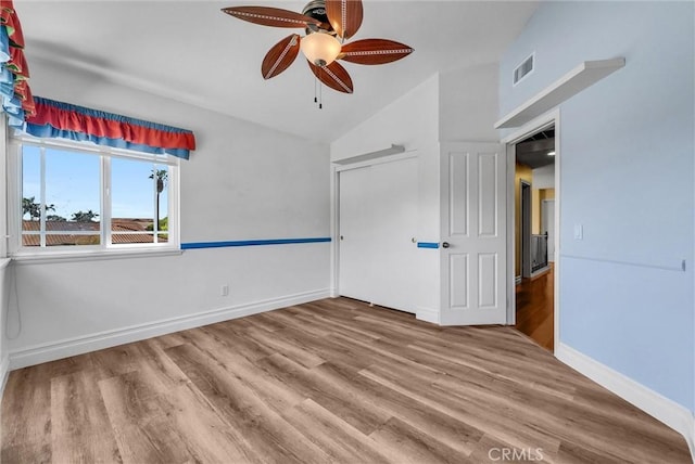 interior space with lofted ceiling, visible vents, baseboards, wood finished floors, and a ceiling fan