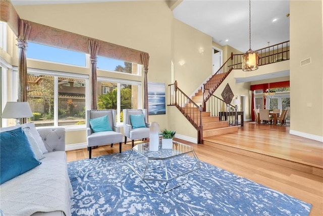 living area featuring a towering ceiling, wood finished floors, stairway, and baseboards