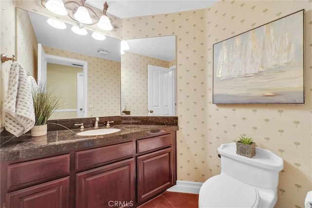 bathroom with visible vents, wallpapered walls, toilet, vanity, and tile patterned flooring