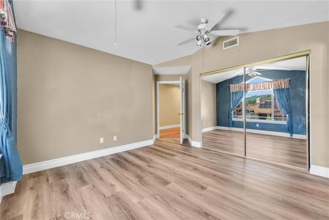 unfurnished bedroom featuring ceiling fan, wood finished floors, visible vents, baseboards, and lofted ceiling