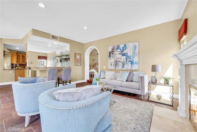 living room with recessed lighting, arched walkways, visible vents, and baseboards