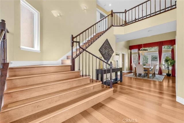 stairway with a high ceiling, wood finished floors, and baseboards