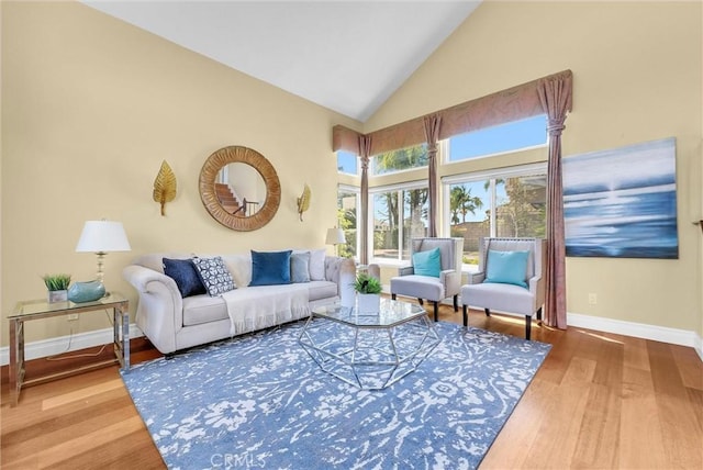 living room with wood finished floors, high vaulted ceiling, and baseboards