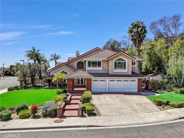 traditional-style house featuring a chimney, a tile roof, a front lawn, concrete driveway, and an attached garage