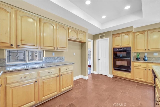 kitchen featuring light stone countertops, light brown cabinetry, visible vents, baseboards, and dobule oven black