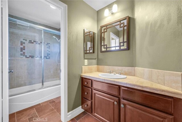 bathroom featuring enclosed tub / shower combo, tile patterned flooring, and vanity
