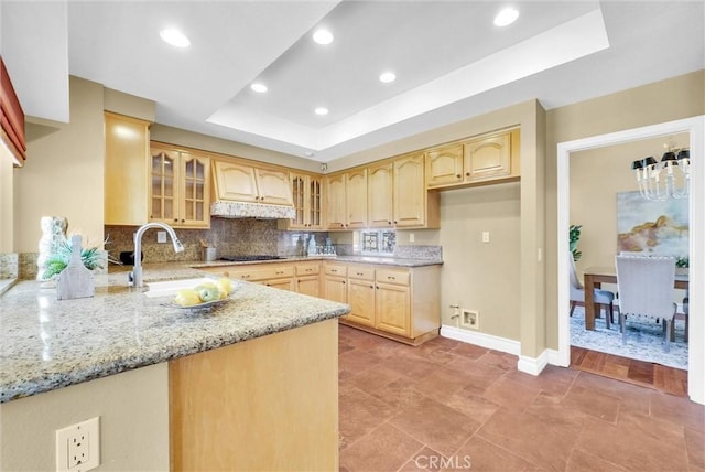 kitchen with custom exhaust hood, light brown cabinets, a sink, gas cooktop, and a tray ceiling