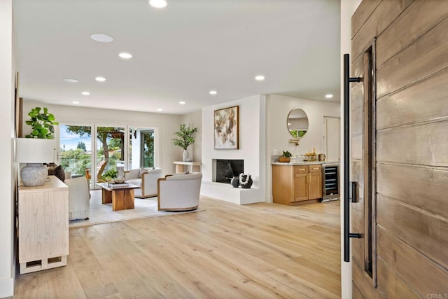 living area with beverage cooler, recessed lighting, and light wood-style flooring