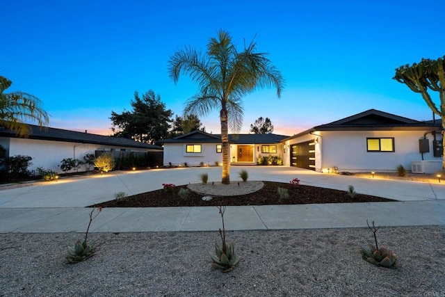 ranch-style house featuring stucco siding, a garage, and curved driveway