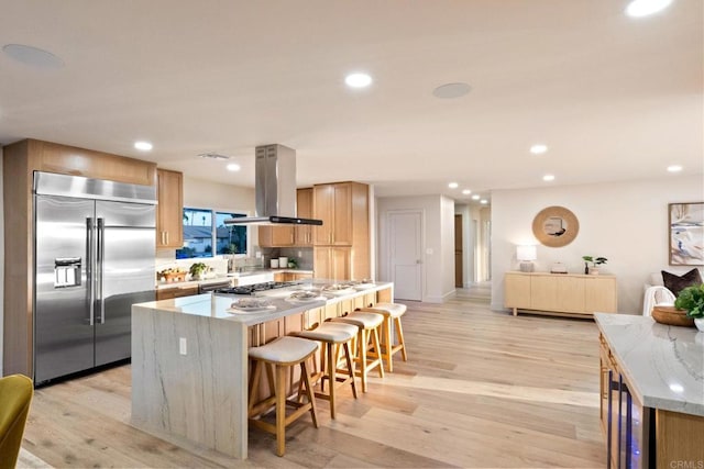 kitchen with island range hood, stainless steel appliances, a kitchen island, and recessed lighting