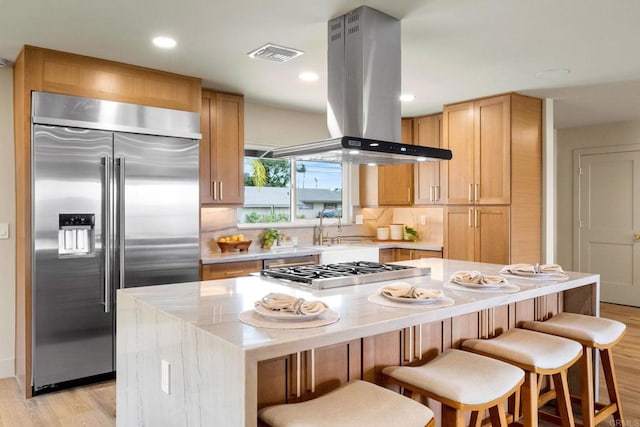 kitchen featuring visible vents, island range hood, appliances with stainless steel finishes, and light wood-style flooring