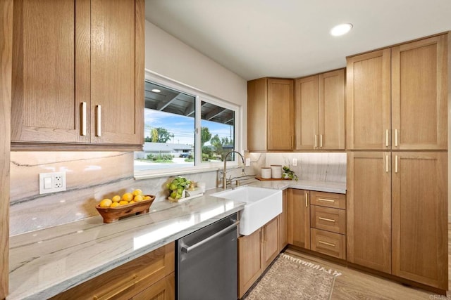 kitchen featuring light wood finished floors, light stone countertops, a sink, tasteful backsplash, and dishwasher