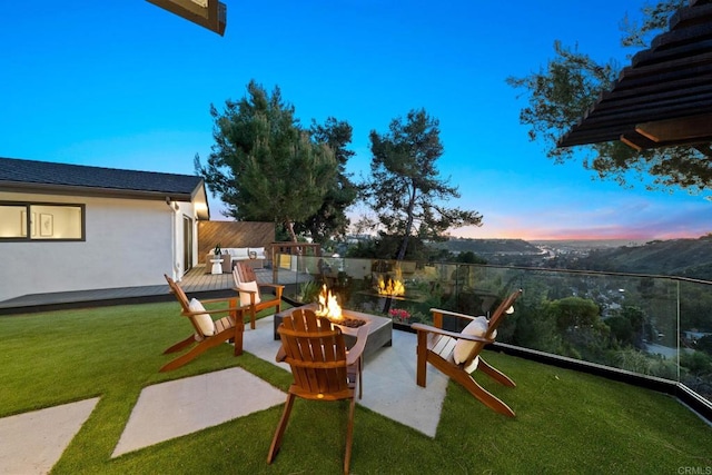 yard at dusk featuring a deck and a fire pit