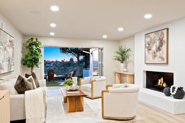 living room with recessed lighting, visible vents, light wood-style flooring, and a warm lit fireplace