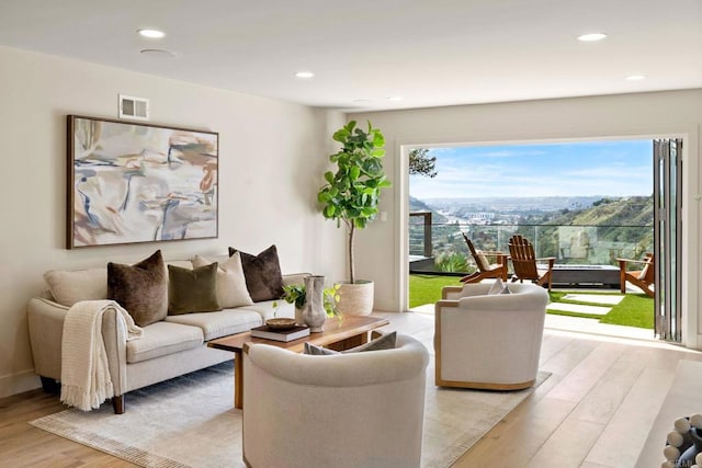 living area featuring visible vents, light wood-type flooring, and recessed lighting