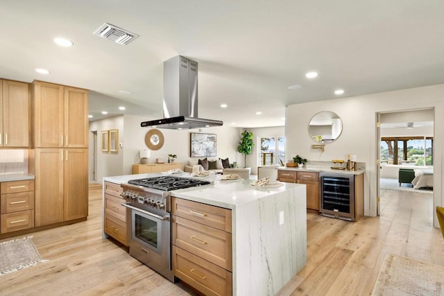 kitchen with island range hood, beverage cooler, high end stainless steel range oven, and light wood finished floors