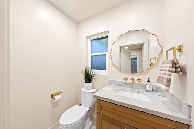 half bath featuring toilet, vanity, and baseboards