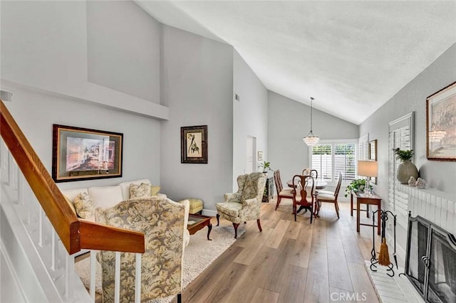 9 Las Piedras, Rancho Santa Margarita, CA 92688 - living area featuring light wood-type flooring, high vaulted ceiling, baseboards, visible vents, and a brick fireplace