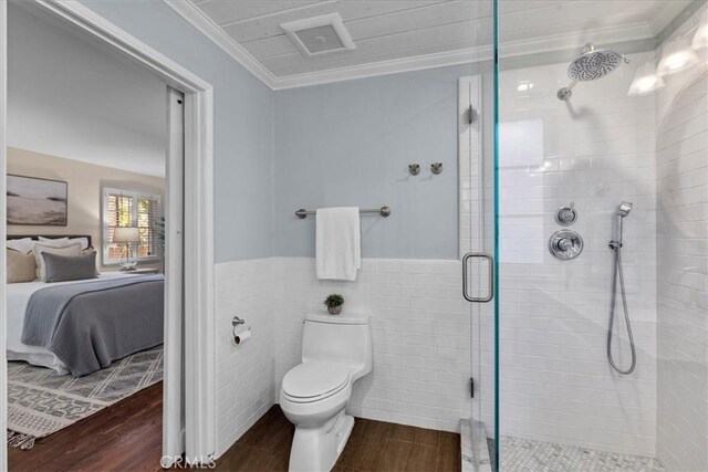 bathroom with toilet, ornamental molding, a shower stall, connected bathroom, and wood finished floors