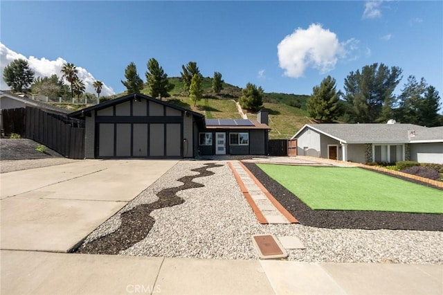 view of front facade with solar panels, fence, driveway, and a garage