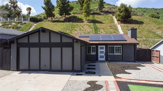 ranch-style home featuring brick siding, solar panels, an attached garage, and concrete driveway