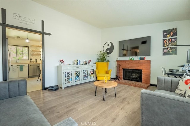 living room with a fireplace, a barn door, and light wood-type flooring