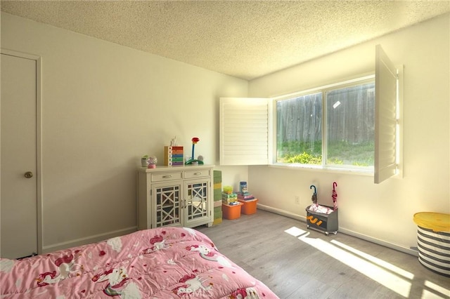 bedroom featuring wood finished floors, a textured ceiling, and baseboards