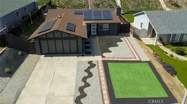 view of front of home with a garage, concrete driveway, fence, and solar panels