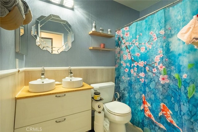 bathroom with a wainscoted wall, vanity, curtained shower, and toilet