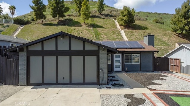ranch-style home with solar panels, concrete driveway, fence, brick siding, and an attached garage