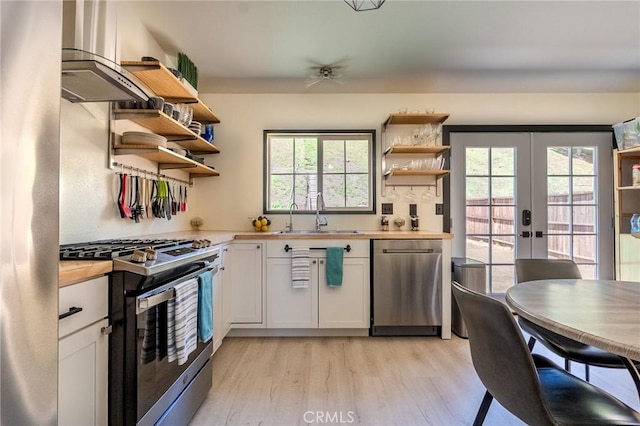 kitchen with light wood-style flooring, open shelves, stainless steel appliances, and a sink