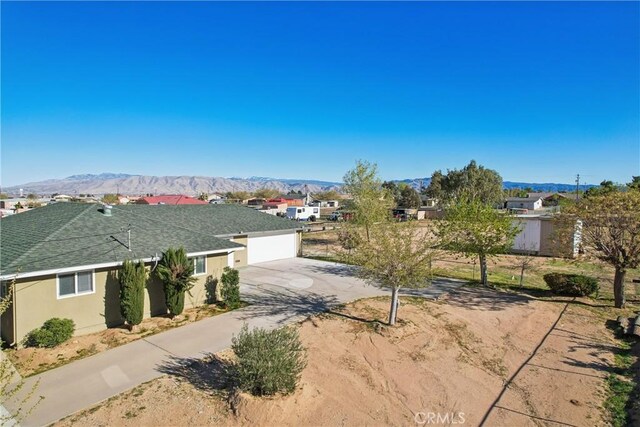 16621 Verano St, Hesperia, CA 92345 - view of front of home with concrete driveway, a shingled roof, a mountain view, and stucco siding