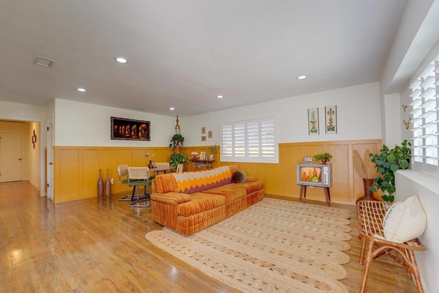 living room featuring a wealth of natural light, wood finished floors, recessed lighting, and wainscoting