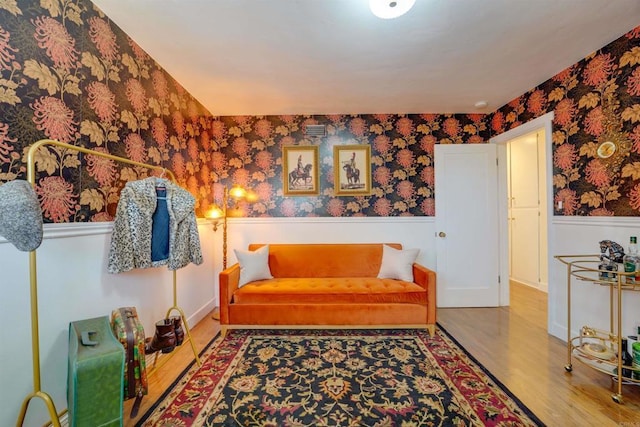 sitting room with wood finished floors, a wainscoted wall, and wallpapered walls