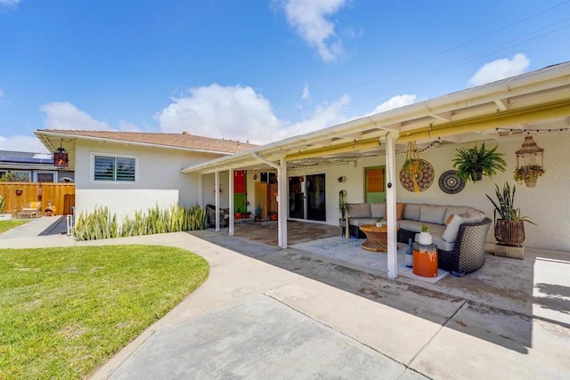 back of property featuring fence, a patio, outdoor lounge area, stucco siding, and a yard