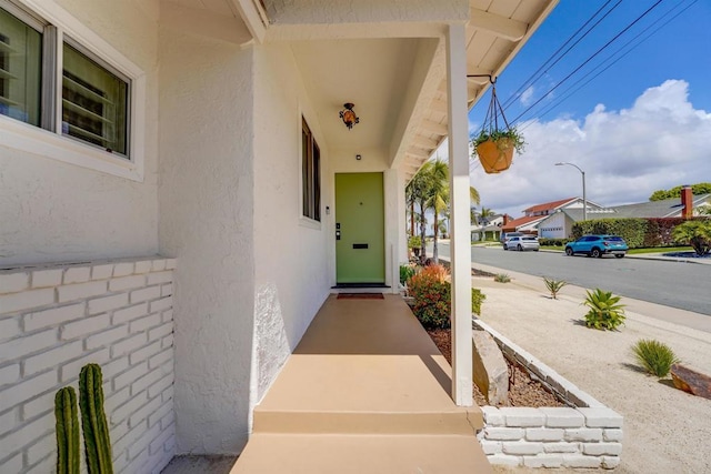 doorway to property with a porch and stucco siding