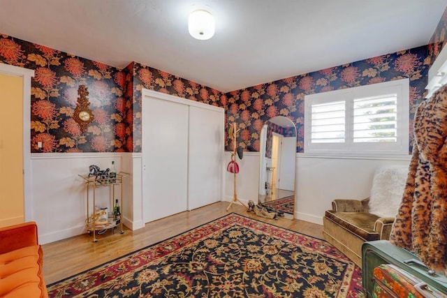 unfurnished room featuring a wainscoted wall, wallpapered walls, and light wood-style floors