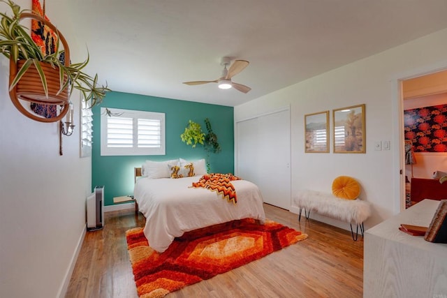 bedroom featuring wood finished floors, ceiling fan, baseboards, and a closet