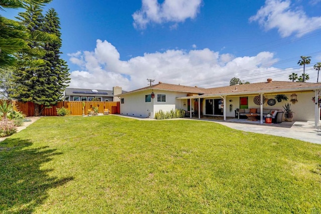 rear view of property with a patio, fence, stucco siding, and a yard