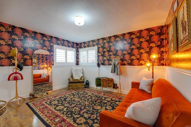 living area with baseboards, light wood-type flooring, wainscoting, and wallpapered walls