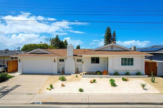 ranch-style home with a garage, a shingled roof, driveway, a chimney, and fence