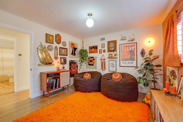 sitting room featuring baseboards, visible vents, and wood finished floors