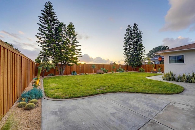 yard at dusk with a patio area and a fenced backyard