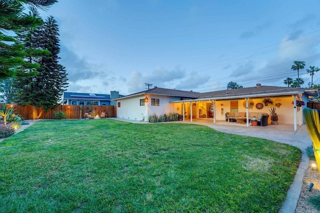 back of property featuring a lawn, stucco siding, a patio, and a fenced backyard