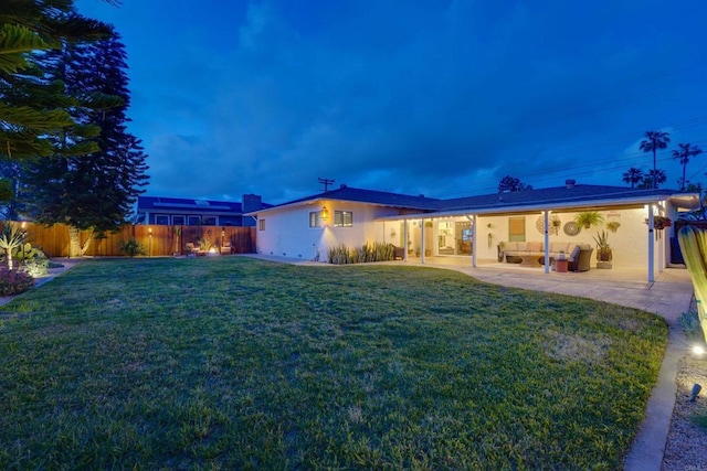 view of front of house featuring a patio, stucco siding, fence, a front lawn, and an outdoor living space