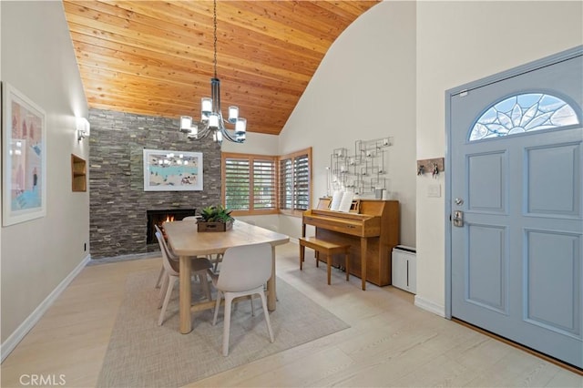 dining area featuring a chandelier, high vaulted ceiling, light wood-style flooring, baseboards, and wood ceiling