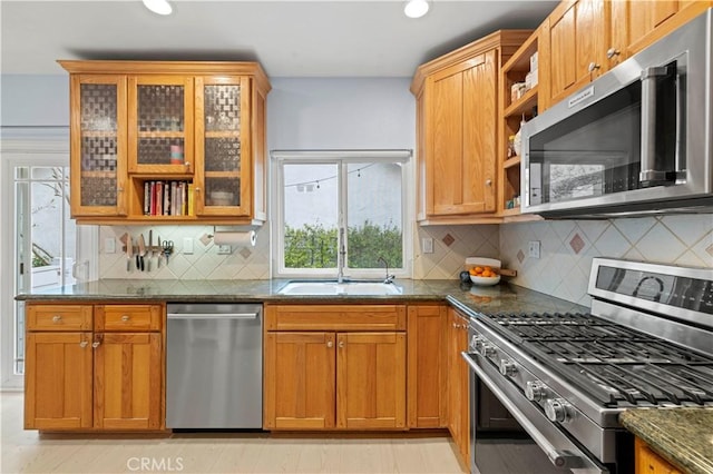 kitchen featuring dark stone counters, open shelves, a sink, stainless steel appliances, and recessed lighting