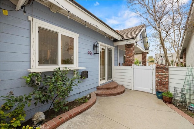 view of property exterior featuring a patio, a gate, and fence