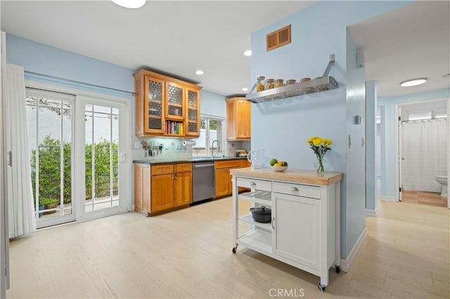 kitchen with a sink, decorative backsplash, light wood-style floors, visible vents, and dishwasher